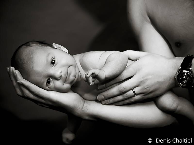 Une photo en noir et blanc d'un bébé allongé sur l'avant-bras d'un de ses parents.